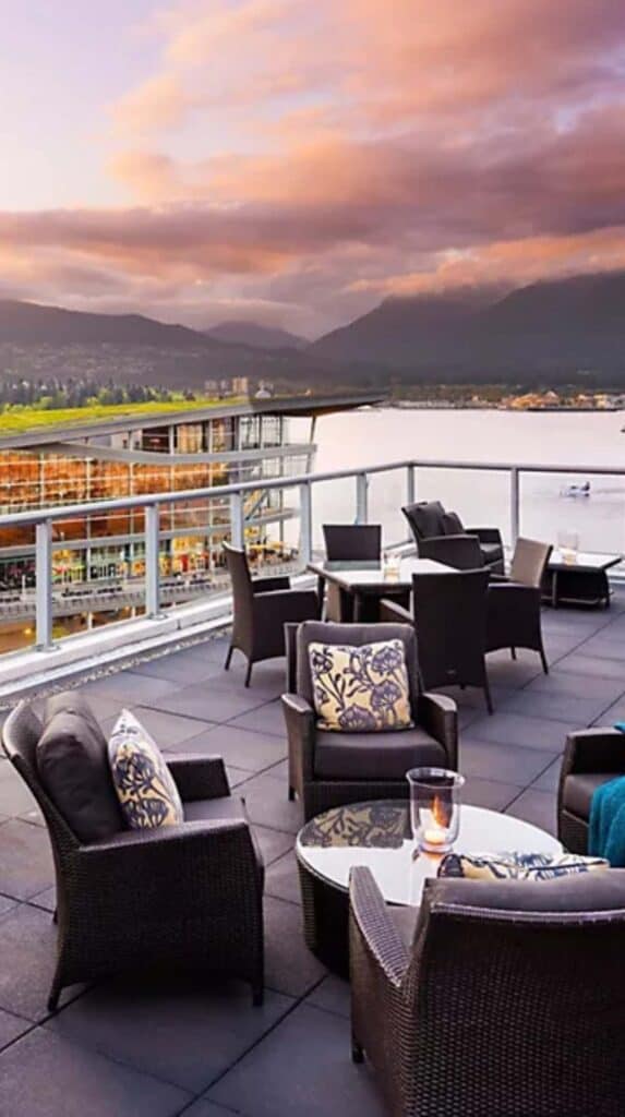 Outdoor terrace seating overlooking Vancouver harbor at sunset near the cruise port.