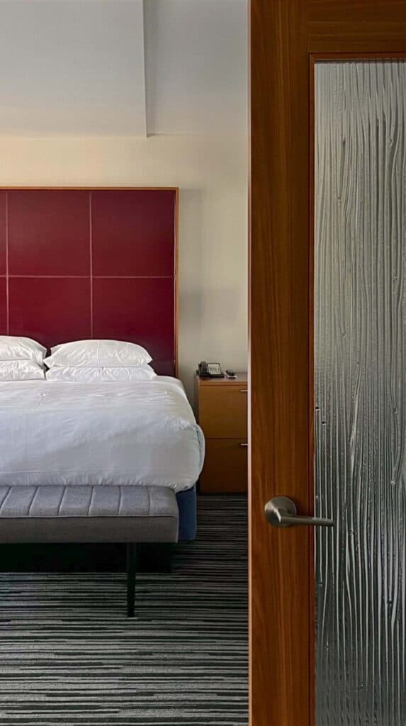 Hotel room with bed viewed through partially open door at a Vancouver cruise port hotel.