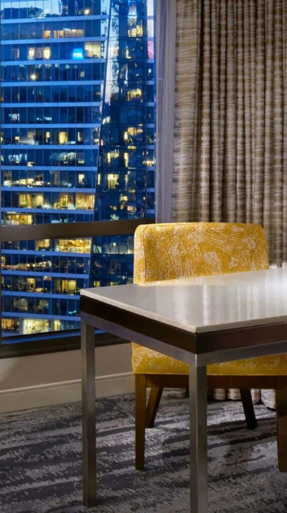 Seating area with yellow chair and city view at night in a Vancouver cruise port hotel.
