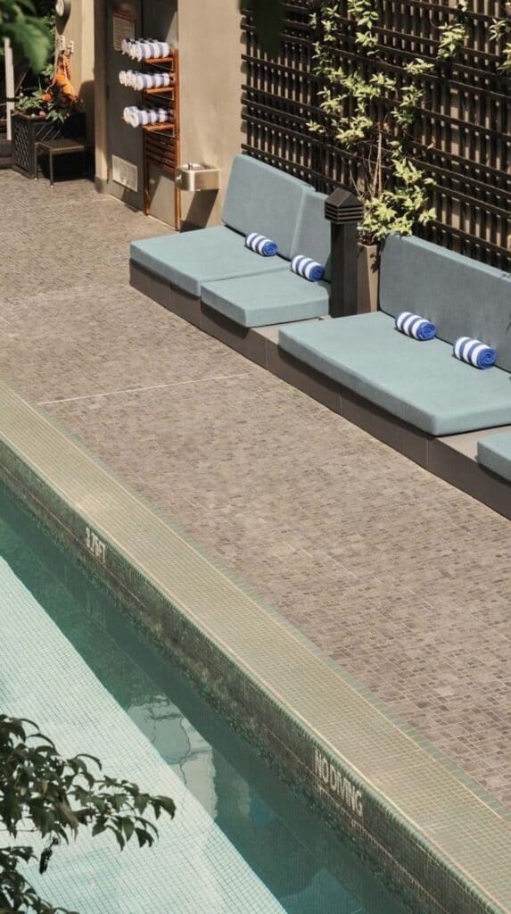Outdoor pool with cushioned lounge seating and greenery at a boutique Vancouver hotel near the cruise port.