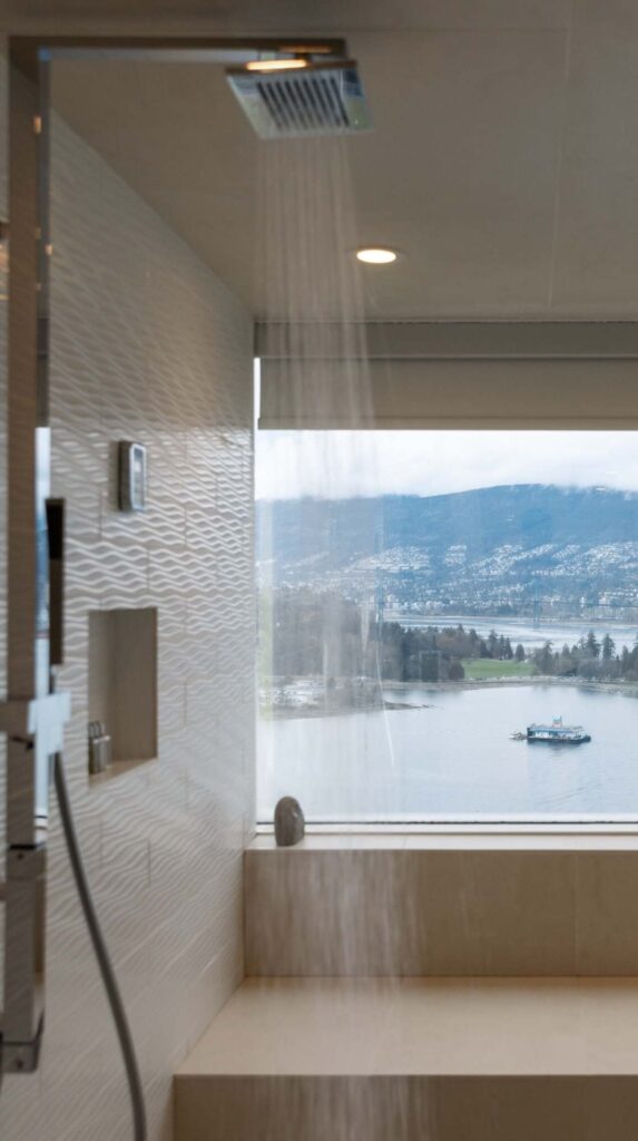 Modern bathroom with walk in shower and large window overlooking Vancouver waterfront.