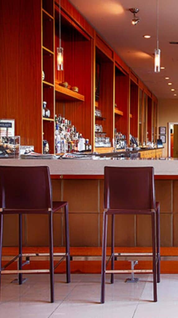 Hotel bar with wood shelving and high stools at a Vancouver cruise port hotel.