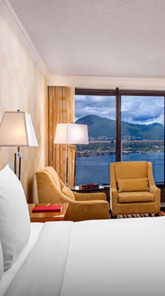 Hotel room with chairs and window overlooking Vancouver harbor and mountains near the cruise port.