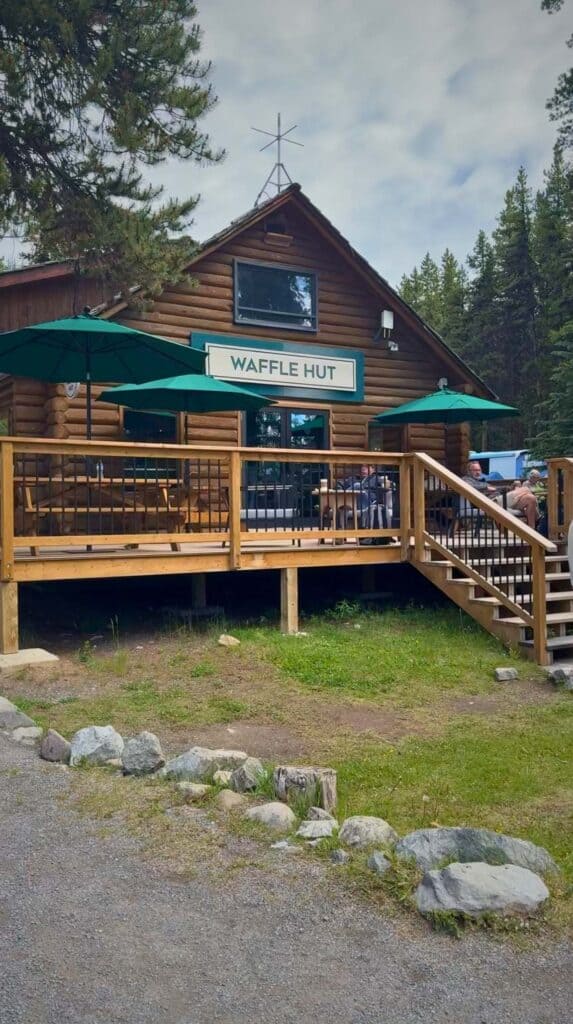 Rustic cabin with a sign reading "Waffle Hut" and outdoor seating area at Maligne Lake.