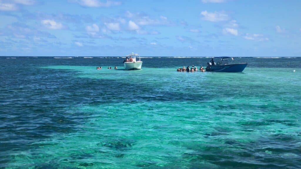 Snorkelers and boats in brilliant turquoise shallows near the best places to stay in Martinique in Le François