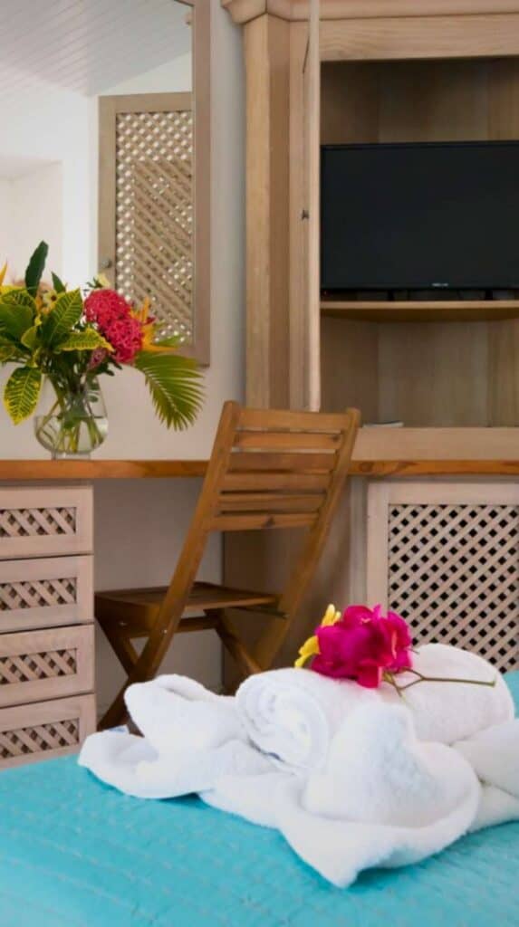 Tropical hotel room with teal bedspread and fresh flowers at one of the hotels in Martinique