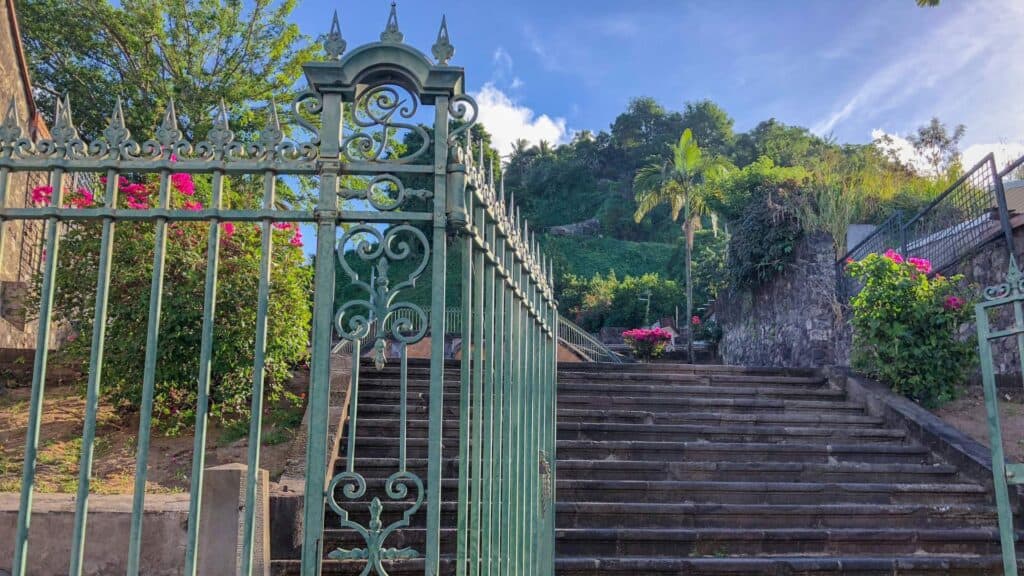 Ornate iron gate opening to a distillery staircase near the best places to stay in Martinique in the north