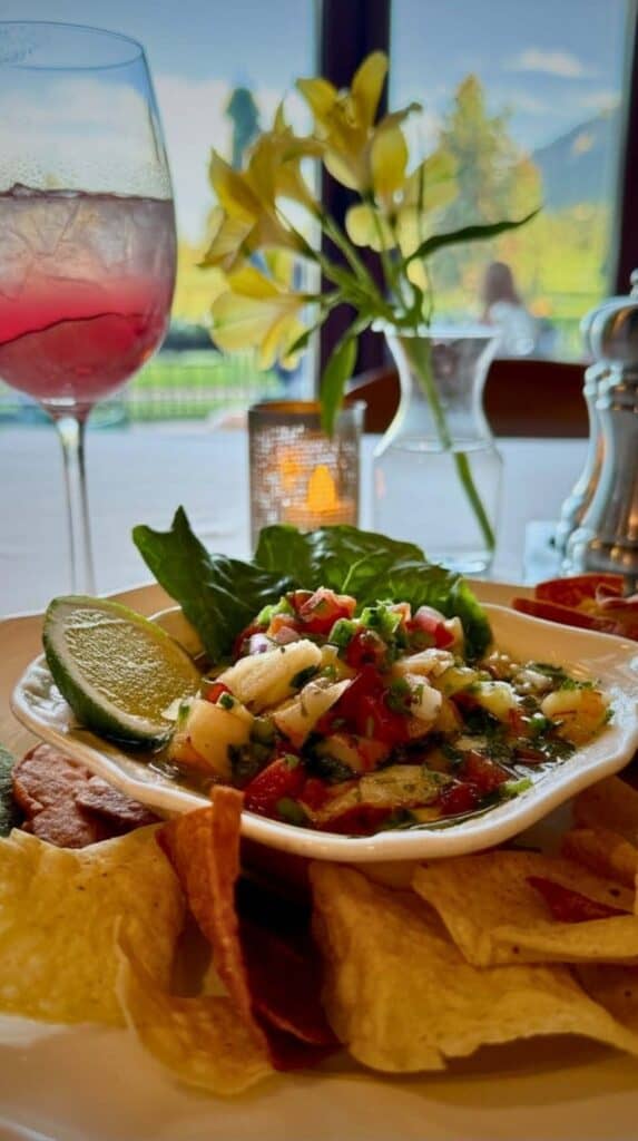 Fresh ceviche with tortilla chips and a pink spritz by the window at the Grille Broadmoor