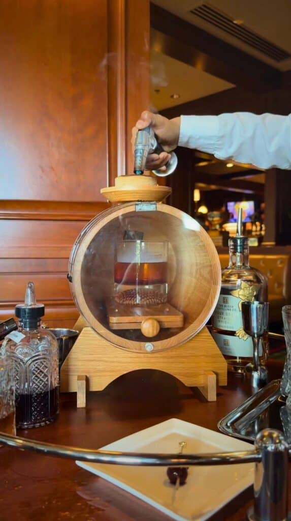 A smoked Grille Old Fashioned prepared tableside under a glass dome at the Grille Broadmoor