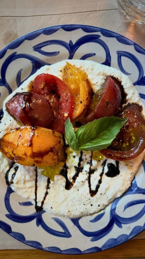 Heirloom tomato and stracciatella with basil on a blue-and-white plate at Ristorante del Lago