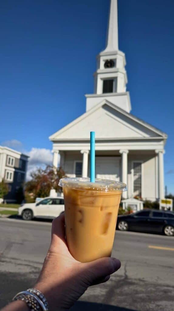 Stowe Community Church framed by a bright blue sky and an iced coffee
