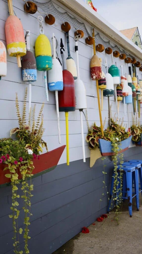 Colorful buoys hang along a weathered shingled wall on Cape Ann
