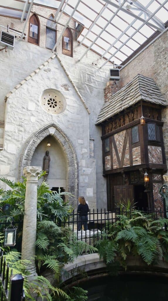 Stone archways draped in greenery inside Hammond Castle in Gloucester
