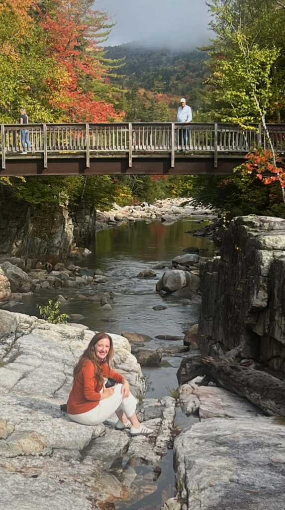 A wooden footbridge crosses a rocky river along the Kancamagus Highway
