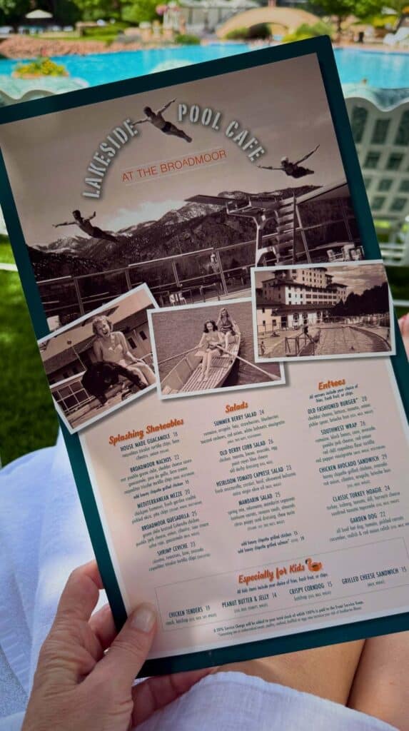 The Lakeside Pool Cafe menu held up with the Broadmoor pool in the background