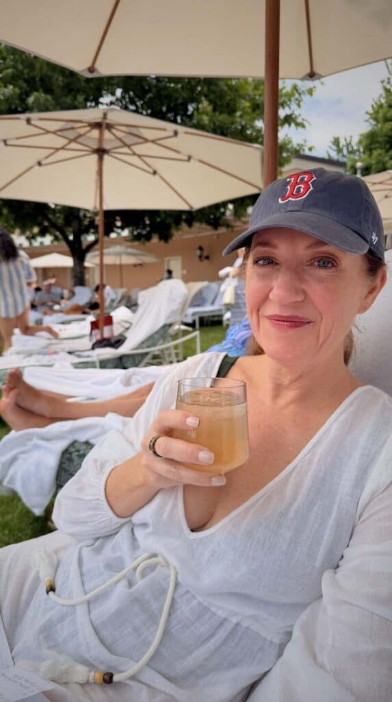 Ashley in a ball cap sipping an Arnold Palmer under an umbrella at the Lakeside Pool Cafe