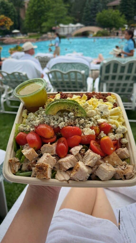 A loaded Derby Cobb salad held over lounge chairs at the Lakeside Pool Cafe