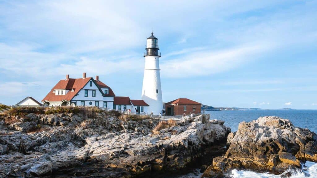 Portland Head Light glows white above the rocky Cape Elizabeth shoreline
