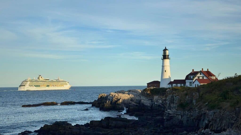 A cruise ship passes a distant lighthouse along the Maine coast
