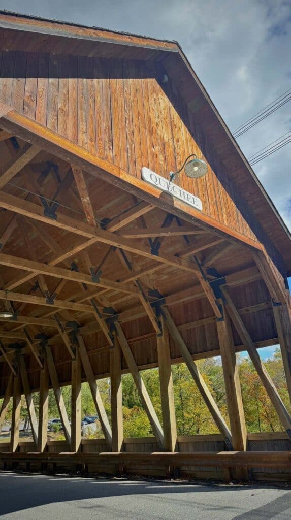 Sunlight streams through the wooden trusses of a Vermont covered bridge

