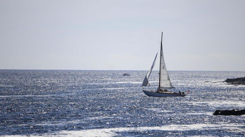 A sailboat glides across calm water near Cape Porpoise, Maine
