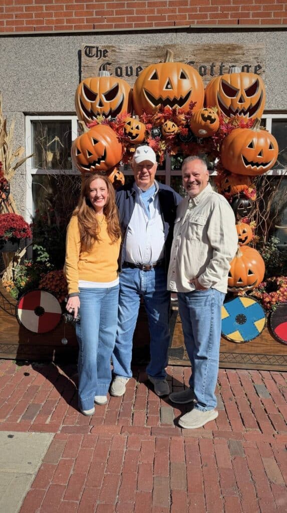 Family posing with jack-o-lantern decorations outside a Salem shop
