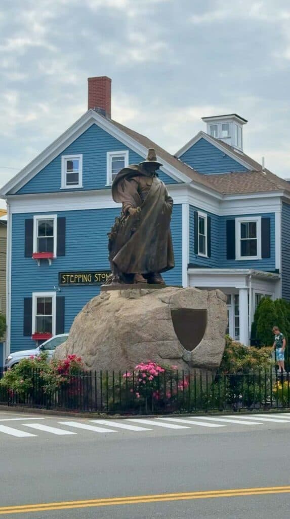 A blue colonial house with a witch statue marks a stop in Salem
