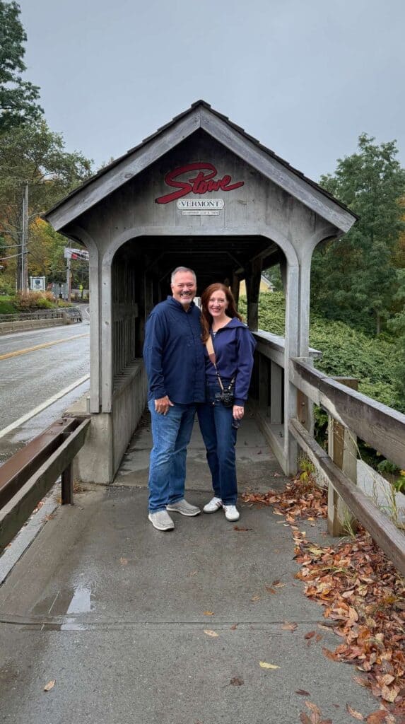 Posing on the historic Stowe covered bridge with fall foliage overhead
