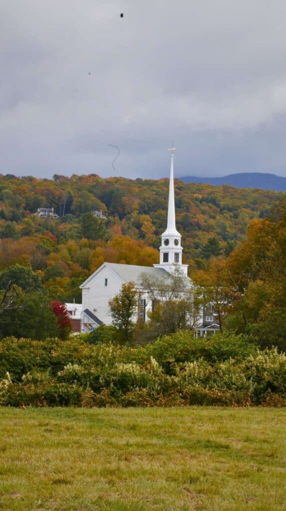 Stowe Community Church's white steeple rises above a Green Mountains backdrop
