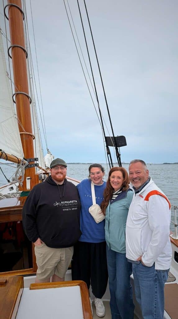 Friends smiling aboard a schooner during a Boston Harbor sunset sail
