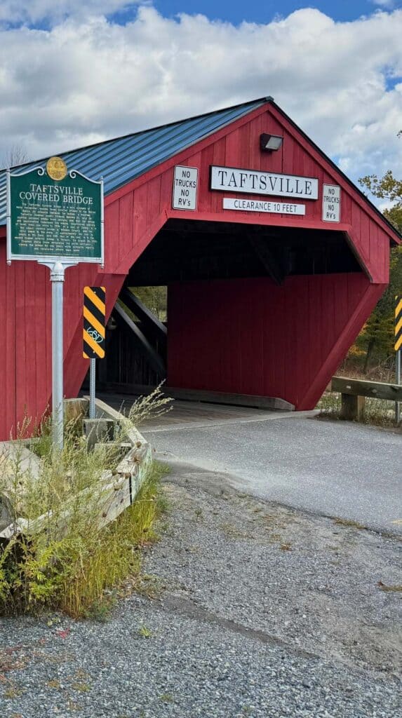 The bright red Taftsville Covered Bridge spans a river in Woodstock, Vermont
