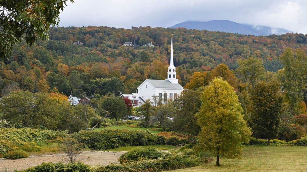 Stowe Community Church steeple rises above fall foliage in the Green Mountains

