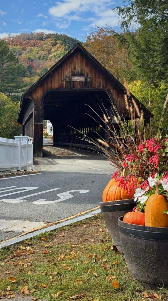 A red covered bridge decorated with pumpkins and mums in Woodstock, Vermont

