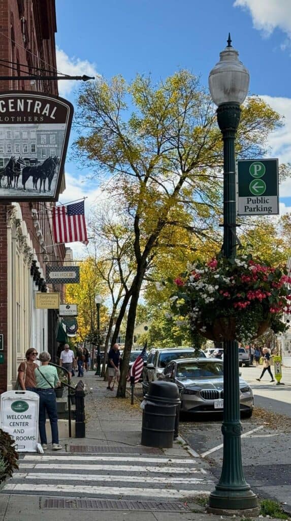 Shoppers walk past storefronts on a tree lined street in Woodstock, Vermont
