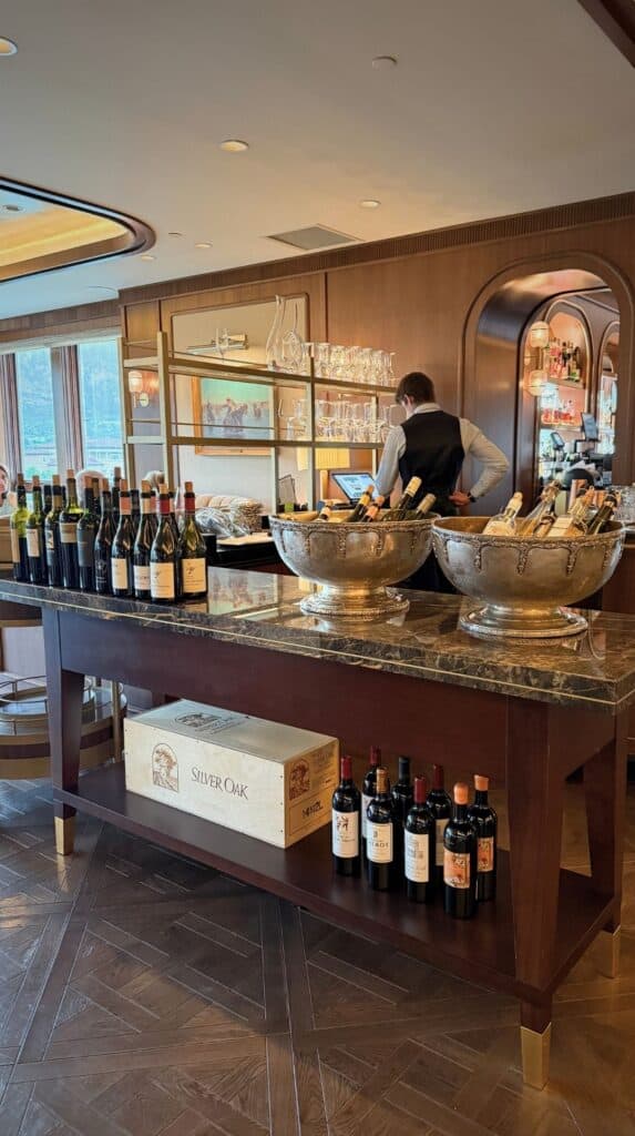 A sommelier pouring wine at the marble service station lined with bottles inside the Penrose Room