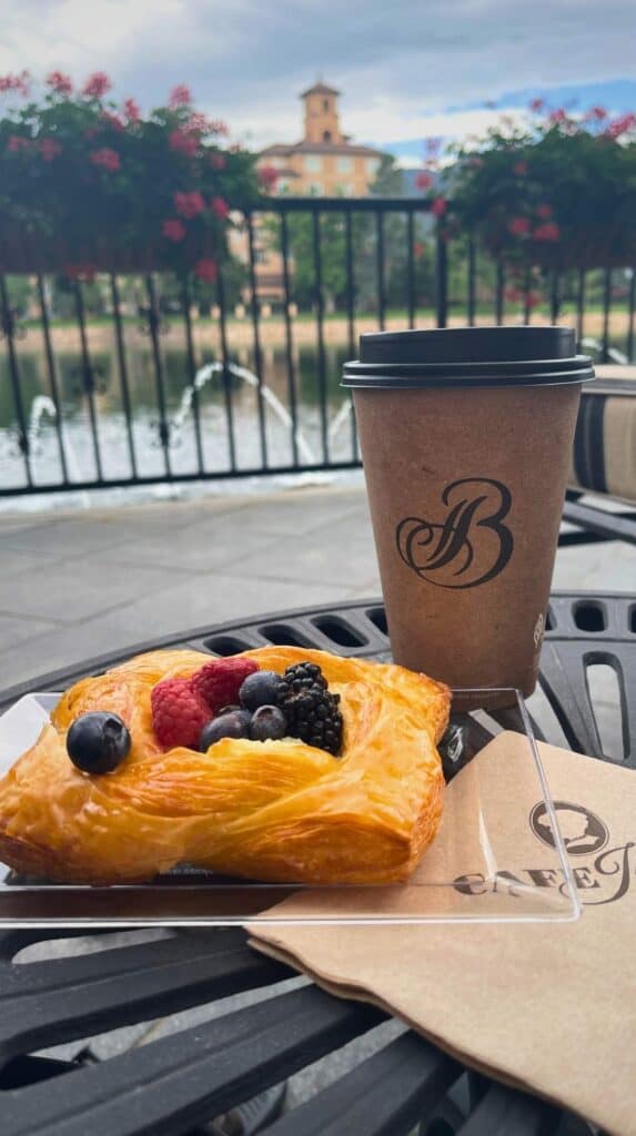 A berry danish and a Broadmoor coffee on a patio table overlooking the lake at Cafe Julie's