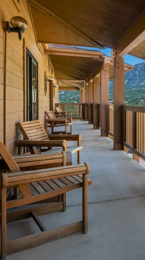 Wooden deck chairs on a balcony with mountain views at the unique hotels in Colorado Springs visitors return to.

