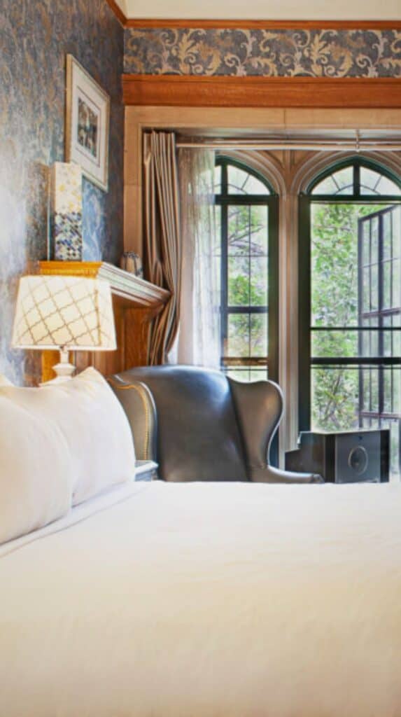 Cozy bedroom with a carved headboard and tall windows at the boutique hotels Colorado Springs travelers seek out.
