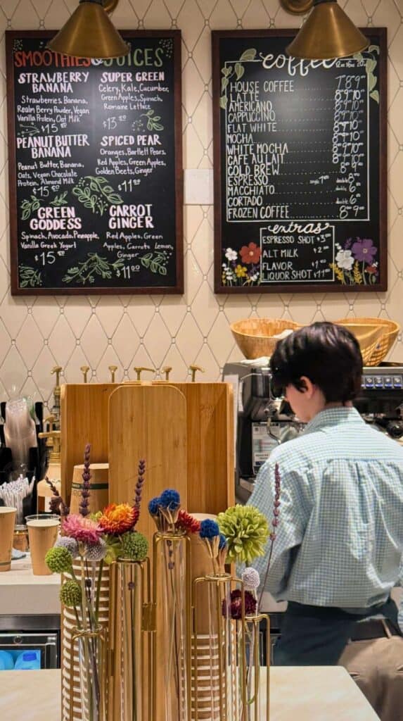 A barista at work below smoothie, juice, and coffee chalkboards at the Natural Epicurean