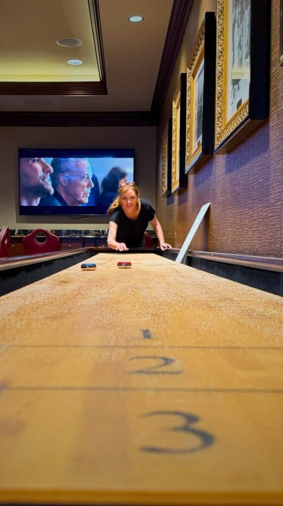 Ashley lining up a shot on the shuffleboard table at PLAY at the Broadmoor