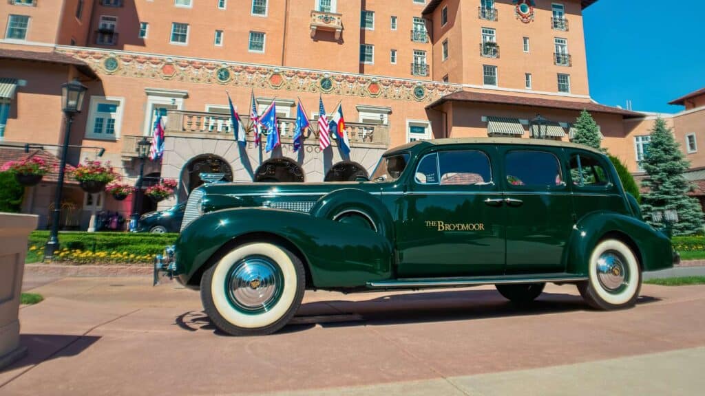 The Broadmoor's vintage green touring car at the flag-lined entrance near the hotel's Broadmoor dining rooms