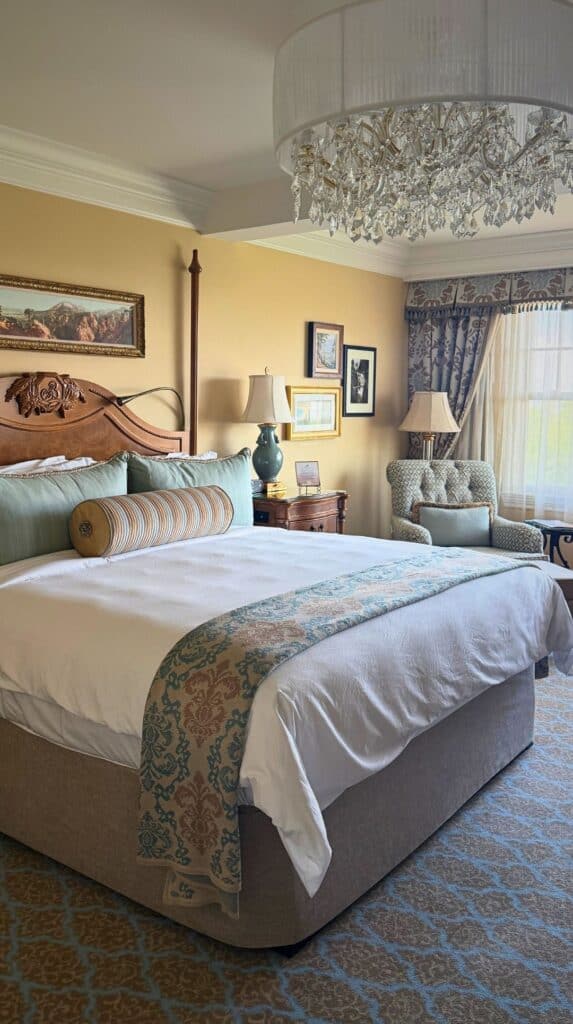 Elegant guest room with teal accents and a carved wood headboard, one of the luxury hotels Colorado Springs offers.
