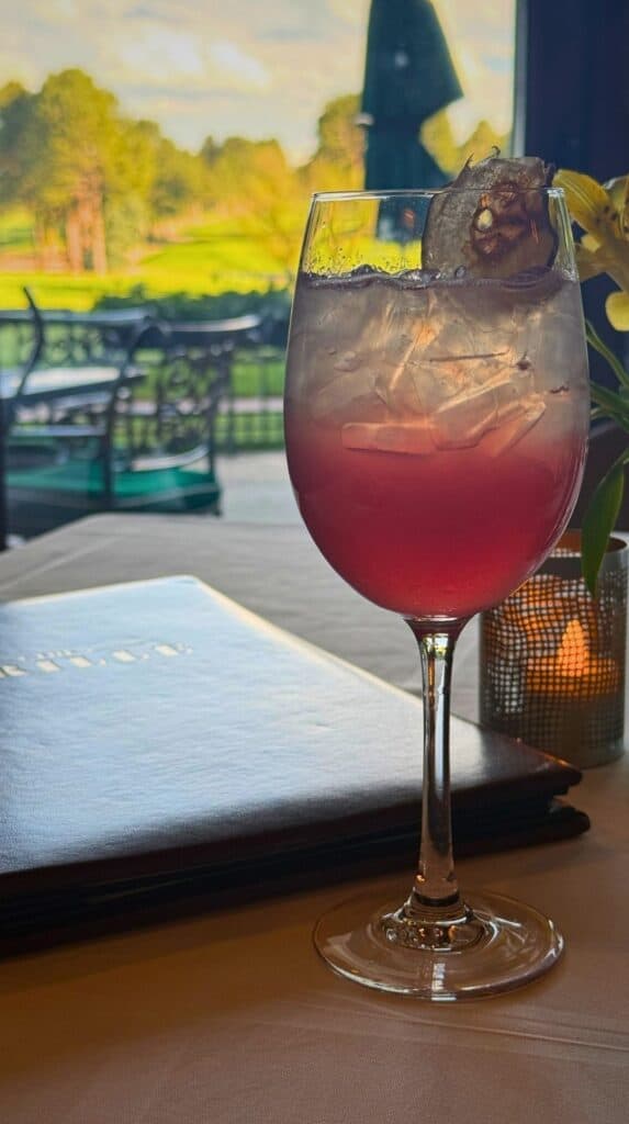 A Club Spritz on the table with the golf course framed in the window at the Grille Broadmoor