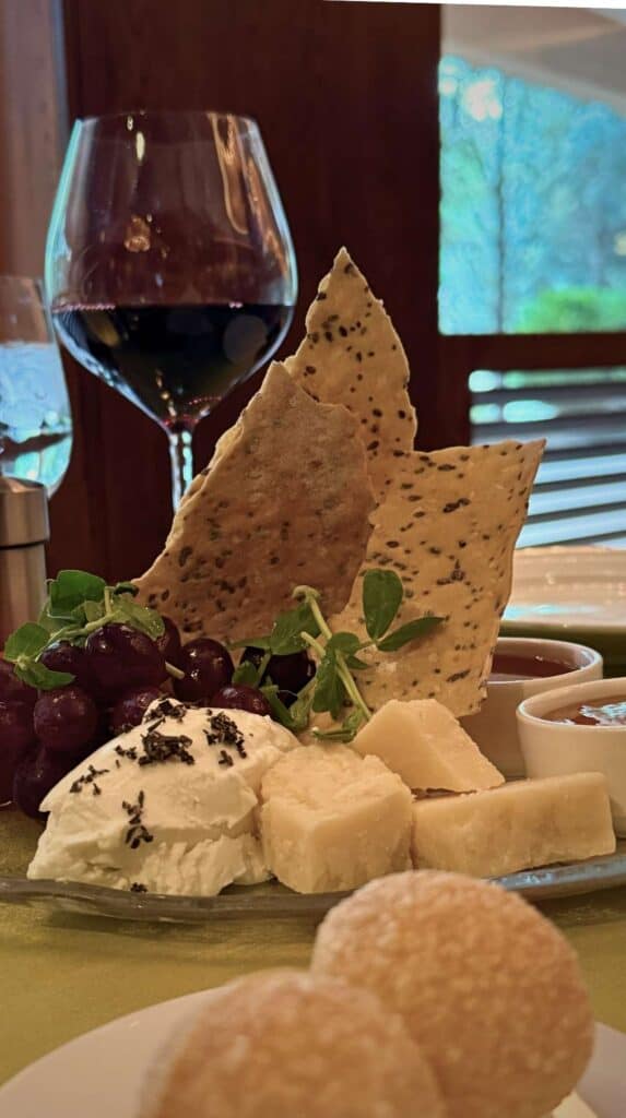 Cheese board with crackers, grapes, and red wine at the Broadmoor Summit restaurant's happy hour