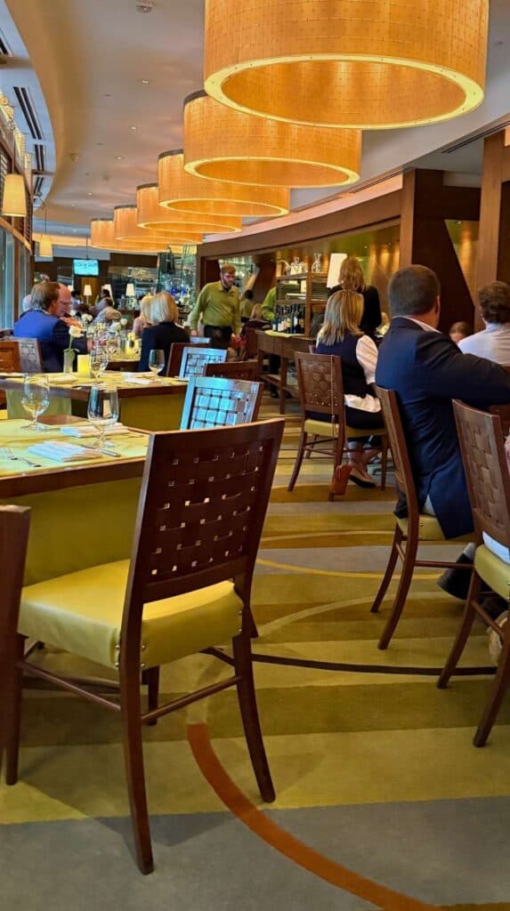 Tiered gold pendant lights above white-linen tables in the Broadmoor Summit restaurant dining room